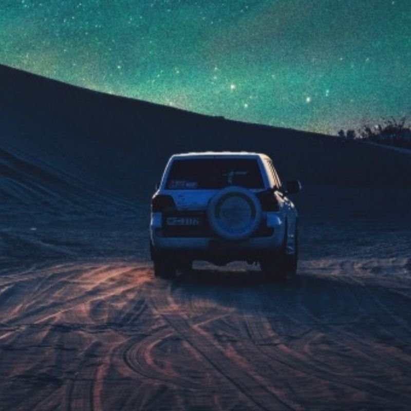 White 4x4 riding through Dubai desert on a night time desert safari tour