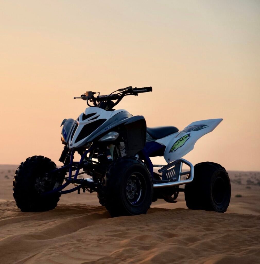 Yamaha Raptor white quad bike parked on the sand dune around sunsert time in Dubai Desert