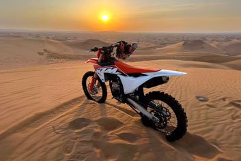 orange color motorcycle KTM 450CC standing on sand dune during sunset