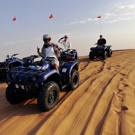 someone posing for camera sitting on blue color yamaha grizzly quad in the desert