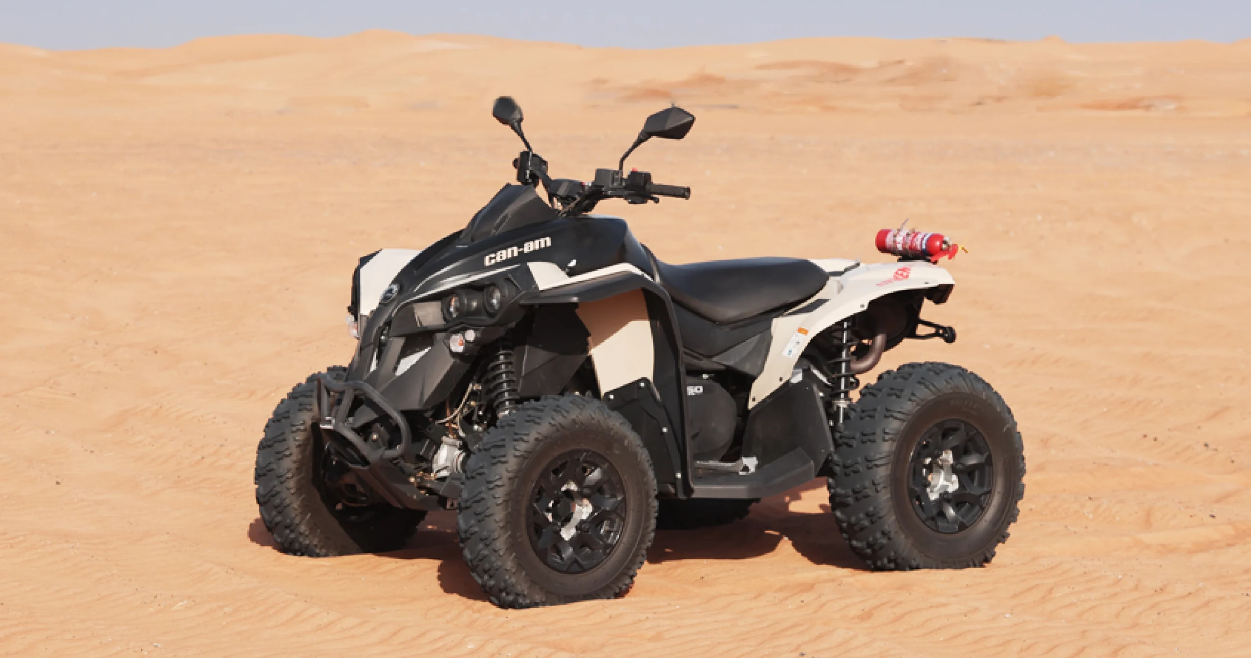 black and white can-am renegade quad sitting idle in desert in dubai